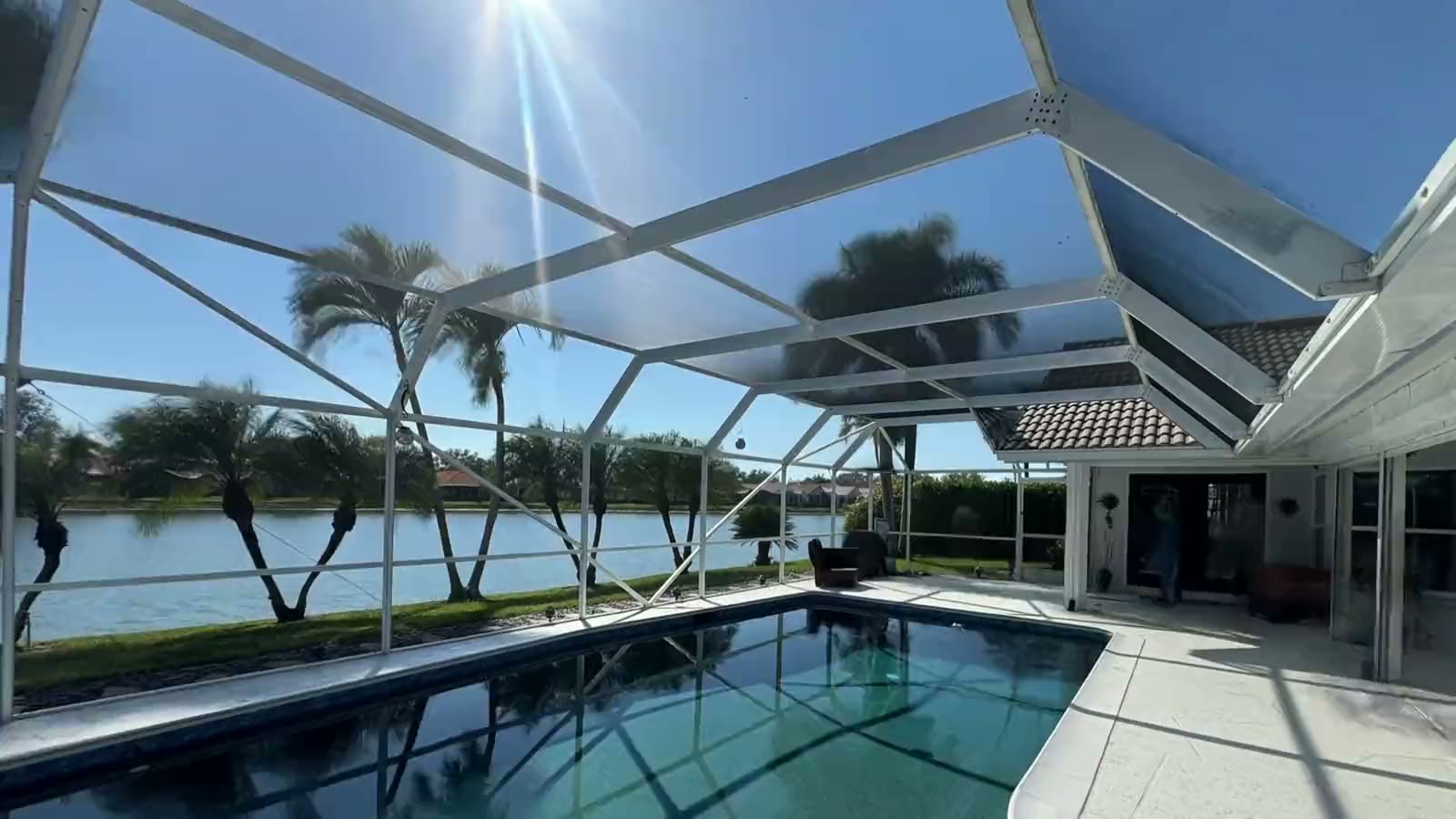 Inside a lakefront pool cage: the faded white aluminum frame over the pool, which is repainted dark bronze with new screen.
