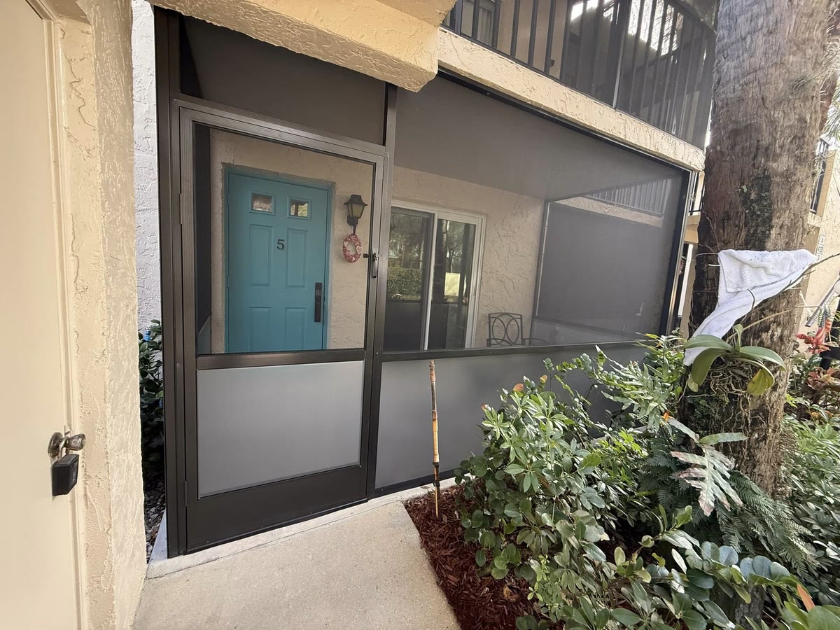 A screened front entry with kick plates, a teal front door inside.