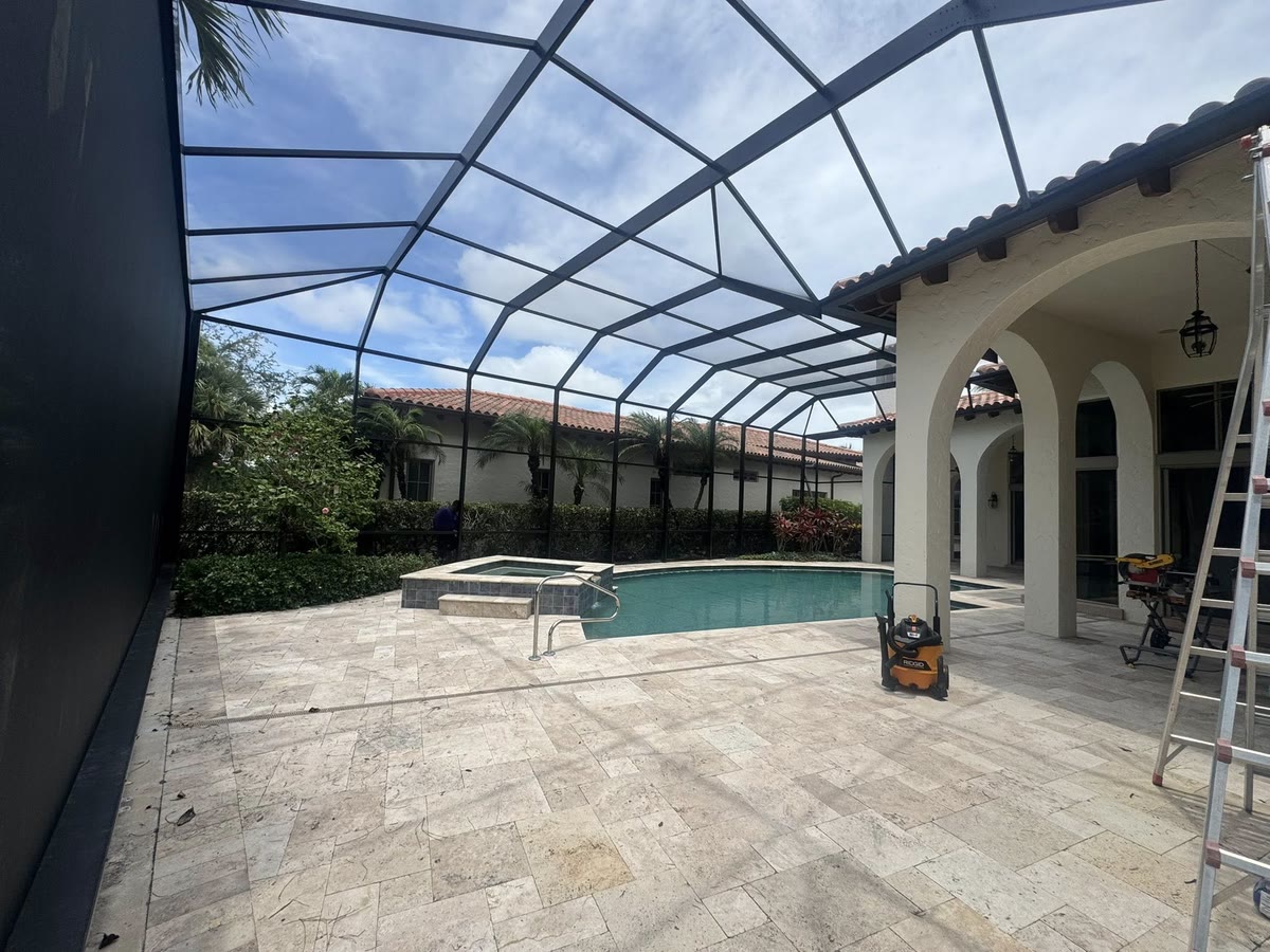 A tall bronze cage over a pale pool deck beside a house with arched doorways.