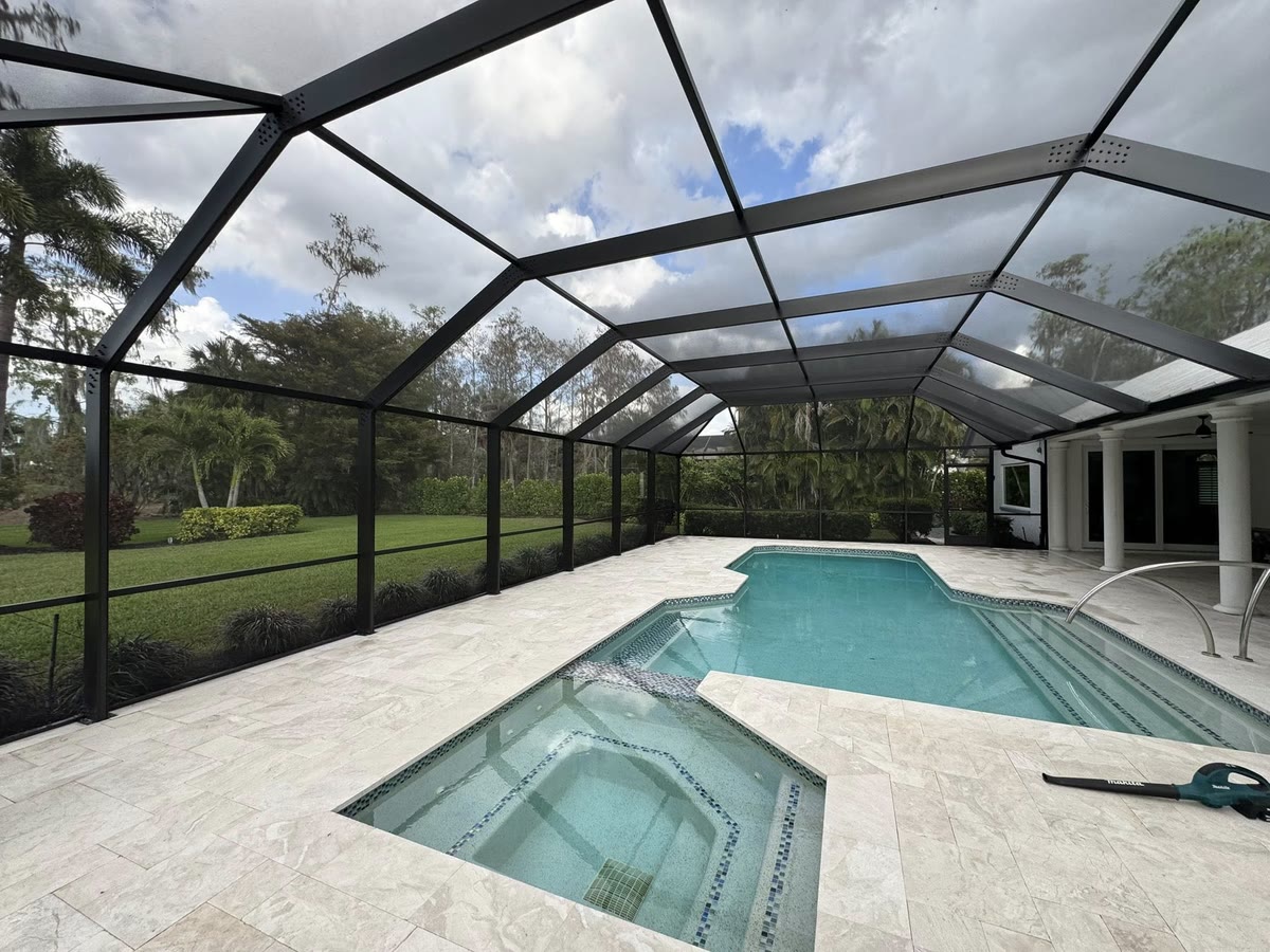 A bronze pool cage over a kidney-shaped pool and spa, a golf course beyond the screen.