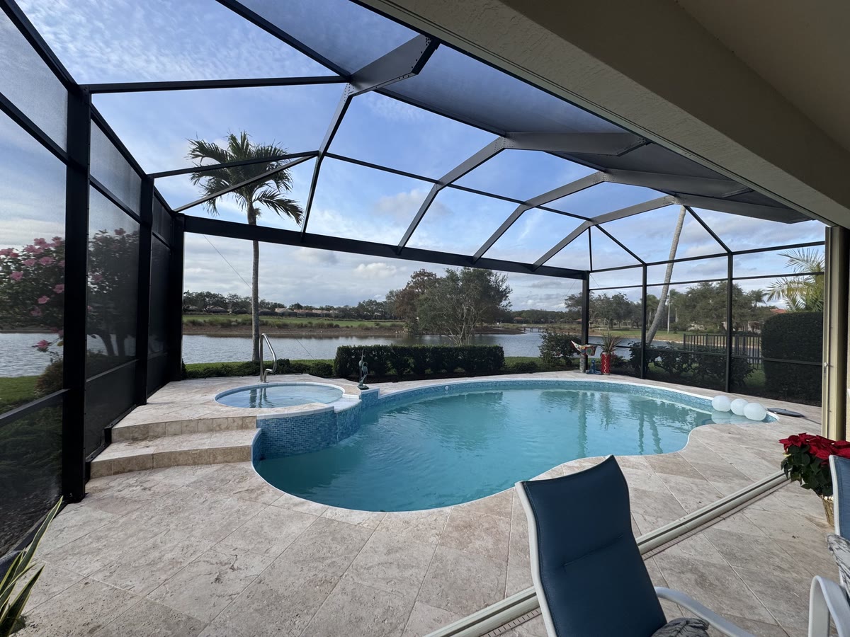 A bronze cage over a curved pool and raised spa, a lake beyond the screen.