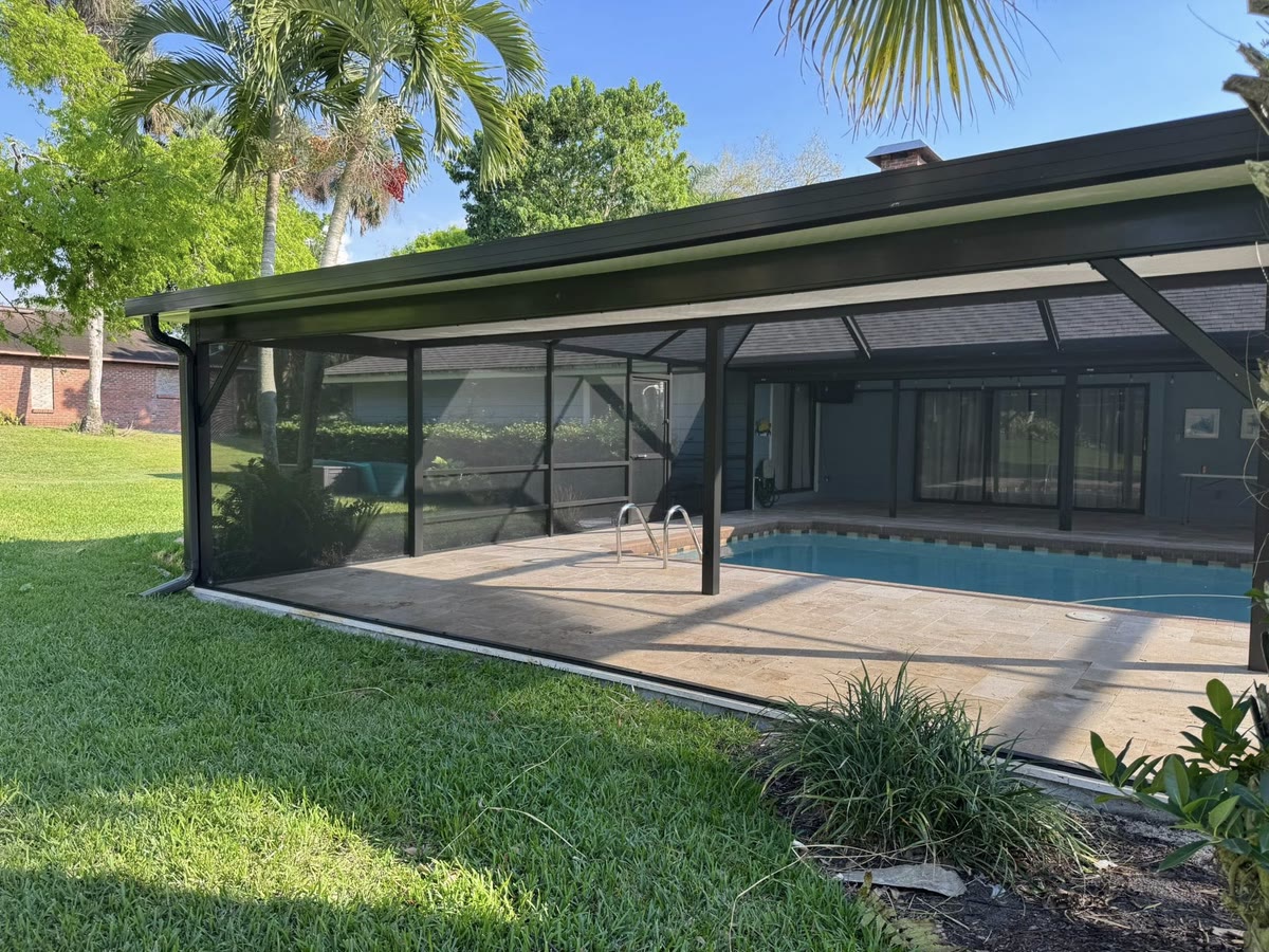 A low bronze pool cage on a wide lawn, seen from outside.