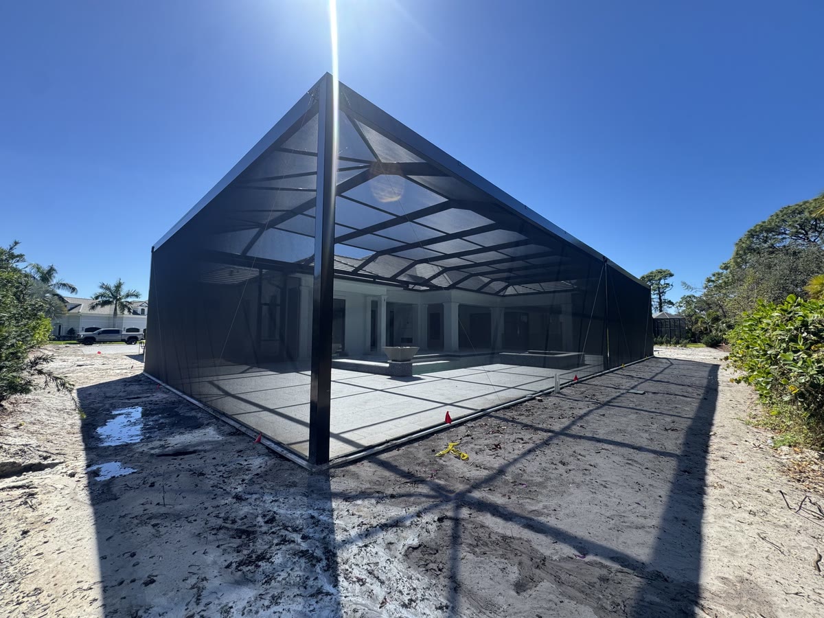 A new bronze cage standing on fresh concrete and sand before the yard is finished.