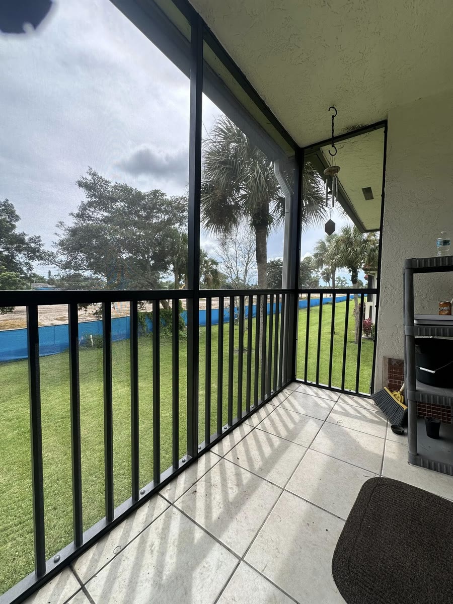 A black aluminum railing around a covered patio, a lake beyond the lawn.