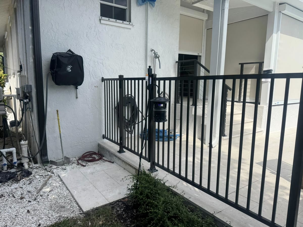 A black aluminum railing and gate around a side landing at a white house.