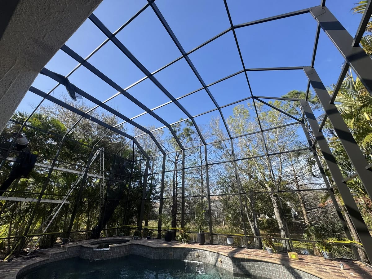 A cage frame with the screens off over a spa, trees and a lake behind it.