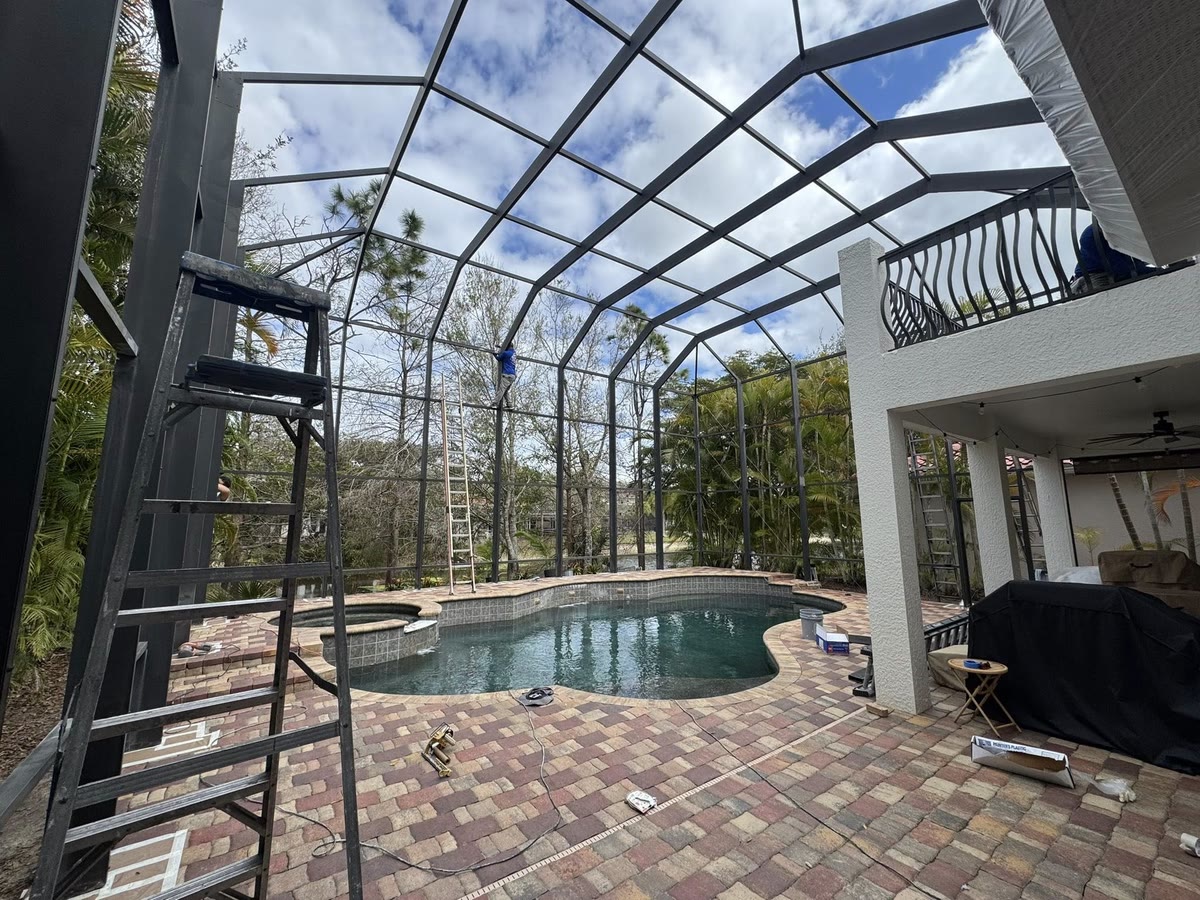 A freshly painted dark cage frame over a pool, a ladder against the frame.