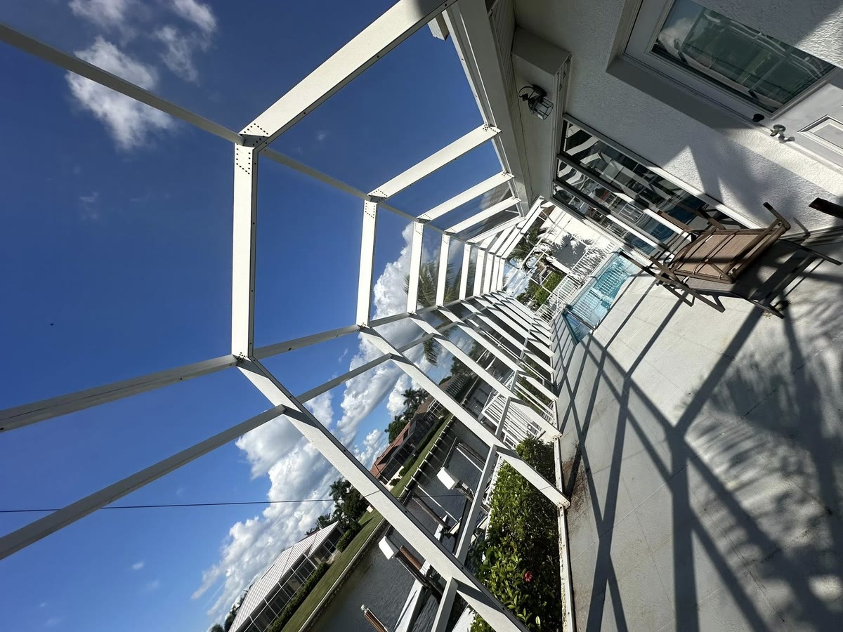 Looking up through a white cage frame along a house wall.