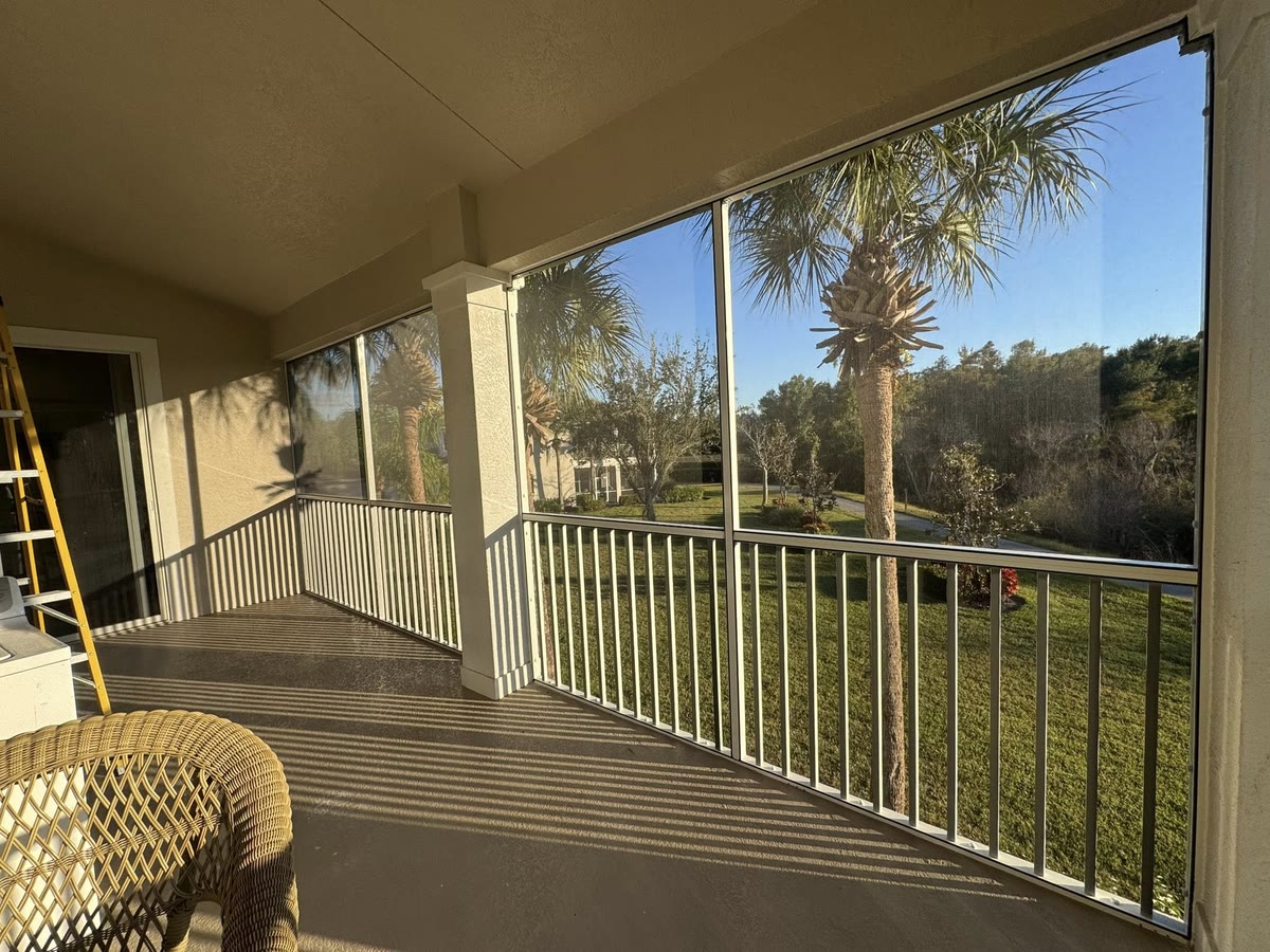 A screened second-floor porch with white railings and a ceiling fan, a ladder still inside.