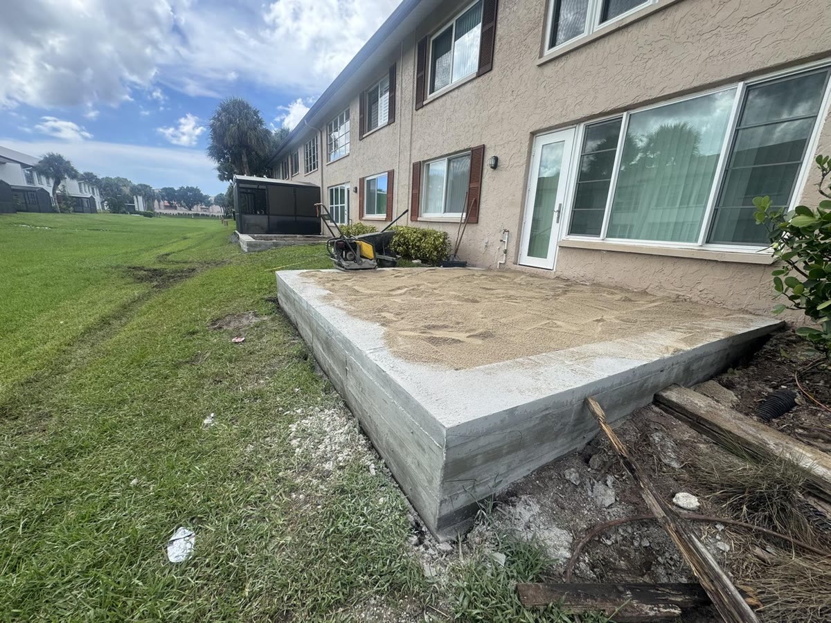 A new raised concrete slab on the lawn behind a ground-floor condo.