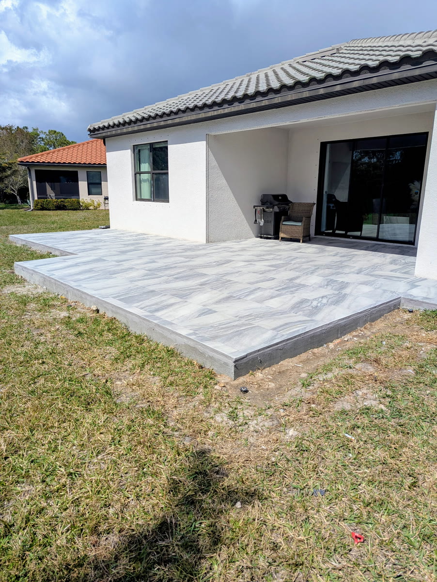 A finished concrete patio slab behind a white house.